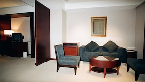 A modern living room with a sofa, armchairs, a coffee table, and a television. - Family Hotel Taipei (New Taipei City)