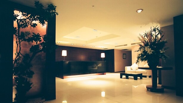 A modern lobby with a reception desk, seating area, and decorative plants. - Family Hotel Taipei (New Taipei City)