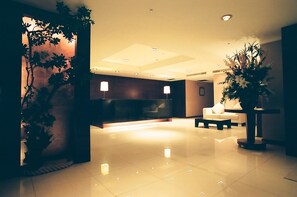 A modern lobby with a reception desk, seating area, and decorative plants. - Family Hotel Taipei (New Taipei City)