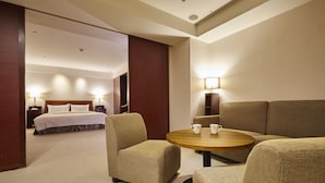A hotel room with a bed, two armchairs, a small round table, and a lamp. - Family Hotel Taipei (New Taipei City)