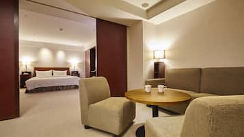 A hotel room with a bed, two armchairs, a small round table, and a lamp.