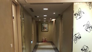 A hotel hallway with a carpeted floor, a painting on the wall, and a floral wallpaper on one side. - Family Hotel Taipei (New Taipei City)