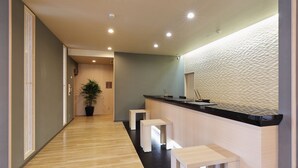 Una moderna zona de recepción con suelo de madera, un mostrador y una planta en maceta.