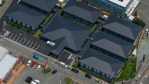 Vista aérea de un edificio comercial con varios estacionamientos e instalación de paneles solares en el techo.