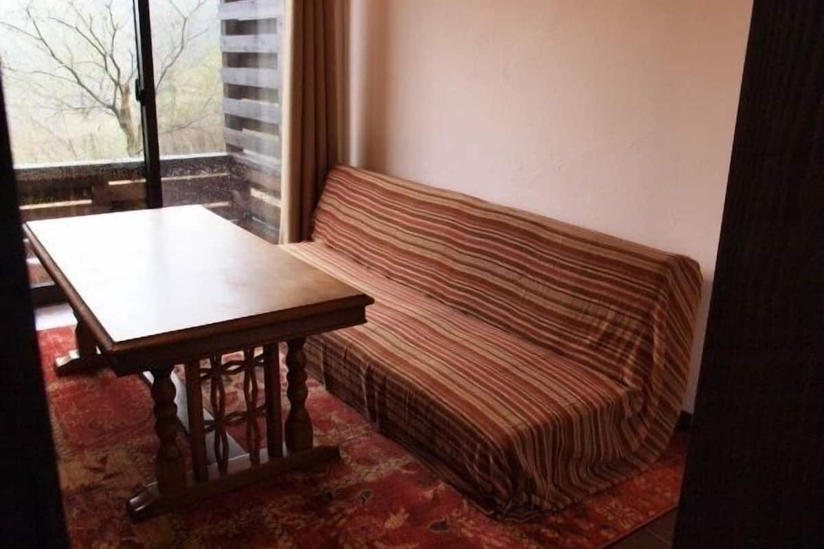 A room with a wooden table, a striped sofa, and a view through a window.