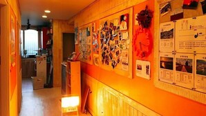 A hallway with a wooden wall adorned with various photos and notices. - SunCheon Guest House ChuChun - Hostel (Suncheon)