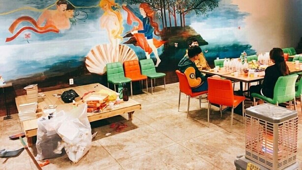 A restaurant with colorful chairs, a mural on the wall, and tables set for dining. - SunCheon Guest House ChuChun - Hostel (Suncheon)
