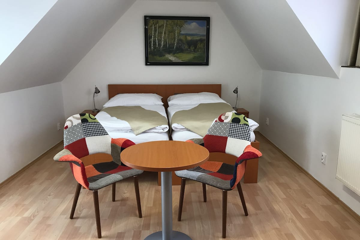 A bedroom with two beds, a round table, and two chairs.