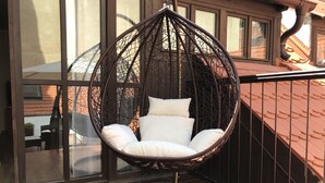 A wicker hanging chair with white cushions on a balcony with tiled flooring. - Old Prague House (Prague)