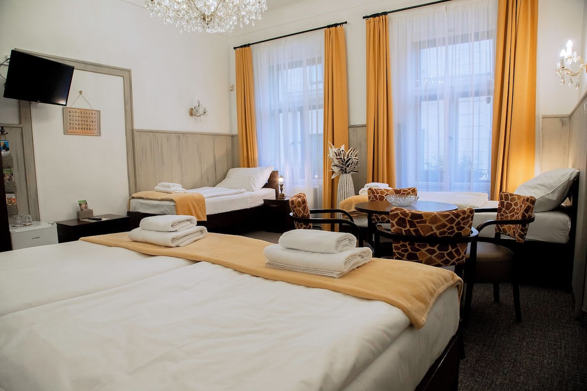 A hotel room with two beds, a desk, a chair, and a television.