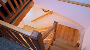 A wooden staircase with a handrail, carpeted steps, and a wall-mounted light fixture. - Old Prague House (Prague)