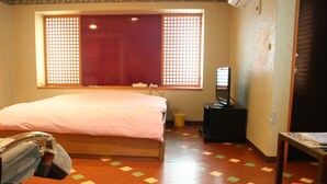 A hotel room with a bed, a desk, a chair, a window with a view, and a trash bin. - Hotel TROPICAL OSAKA - Adults Only (Osaka)