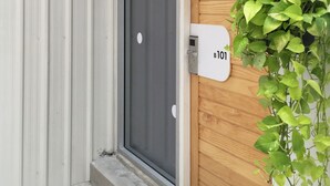 A residential entrance with a grey door, a wooden door, and a mailbox labeled B101. - Movylodge Hostel (Bangkok)