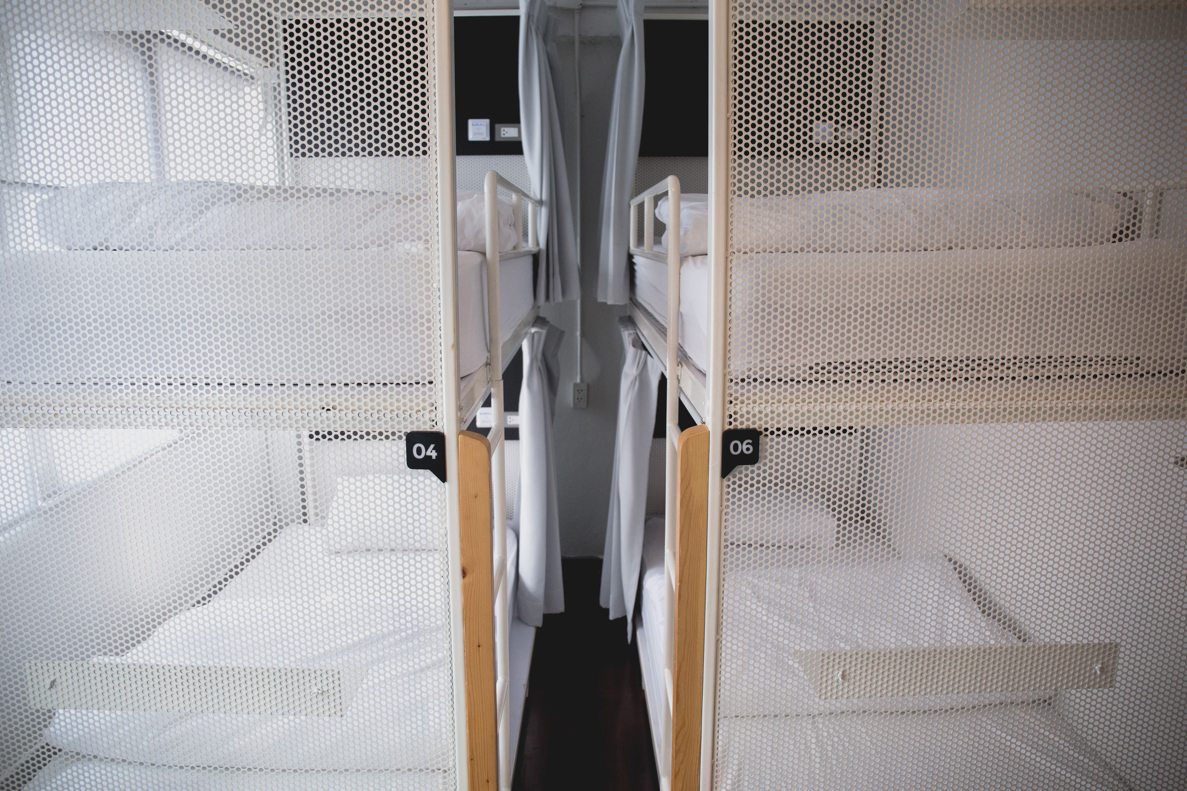 A bunk bed room with a central aisle, numbered beds, and a mesh partition.