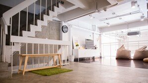 A modern interior with a staircase, a wooden bench, and a green rug. - Movylodge Hostel (Bangkok)