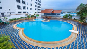 A swimming pool with a tiled deck, surrounded by a building with a red-tiled roof and a white facade. - KP Grand Hotel Chanthaburi (Chanthaburi)
