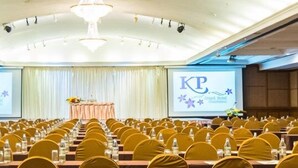 A conference room with rows of tables and chairs, a chandelier, and a screen displaying 'KP Grand Hotel'. - KP Grand Hotel Chanthaburi (Chanthaburi)