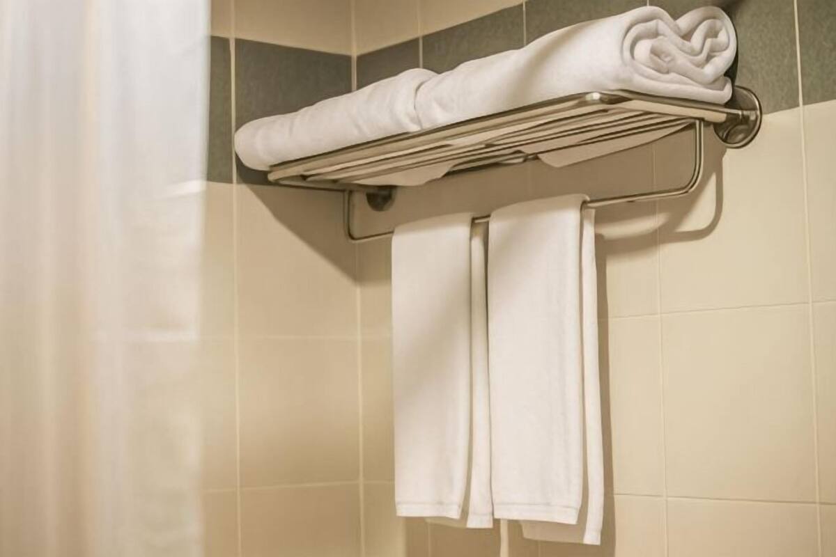 A towel rack with folded towels and a towel hanging on a wall in a bathroom.