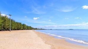 A wide sandy beach with a clear blue sky and calm sea. - KP Grand Hotel Chanthaburi (Chanthaburi)