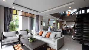 A spacious living area with a sofa, armchairs, and a coffee table. There is a staircase leading to an upper level. - AQUA Villas Rawai (Rawai)
