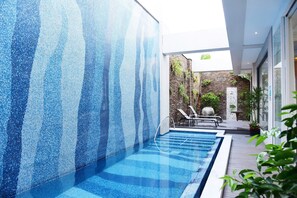 A modern indoor pool with clear blue water, surrounded by a textured blue wall and a wooden deck. - Villa ballet (Taichung)