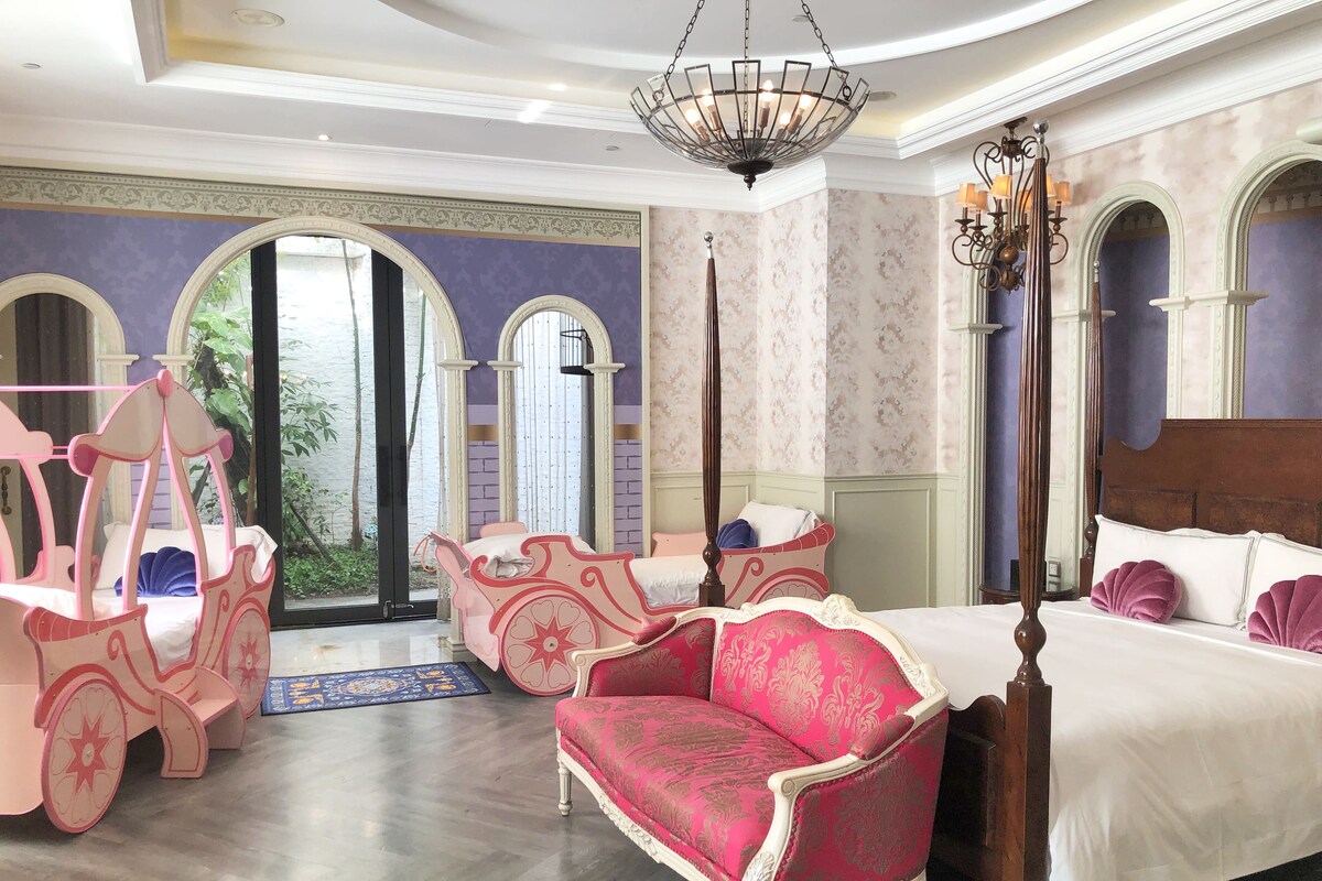 A luxurious bedroom with a large bed, a chaise lounge, and a unique pink carriage-like chair.