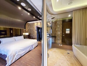A modern hotel room with a large bed, a desk, a bathroom with a bathtub, and a mirror reflecting the room. - Villa ballet (Taichung)