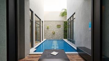 Relax by the serene pool surrounded by lush greenery and natural stone accents.