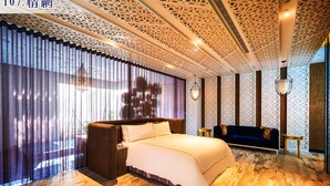 Habitación de hotel con una cama grande, un sofá azul y un techo estampado.