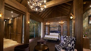Una habitación amplia con una cama grande, un sofá, una mesa redonda y un candelabro.