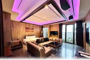 A modern hotel room with a large bed, a sofa, a coffee table, and a TV. - Villa ballet (Taichung)