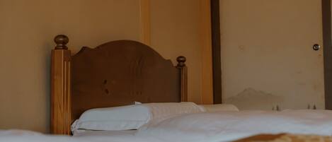 A bed with a wooden headboard, white bedding, and a patterned blanket.