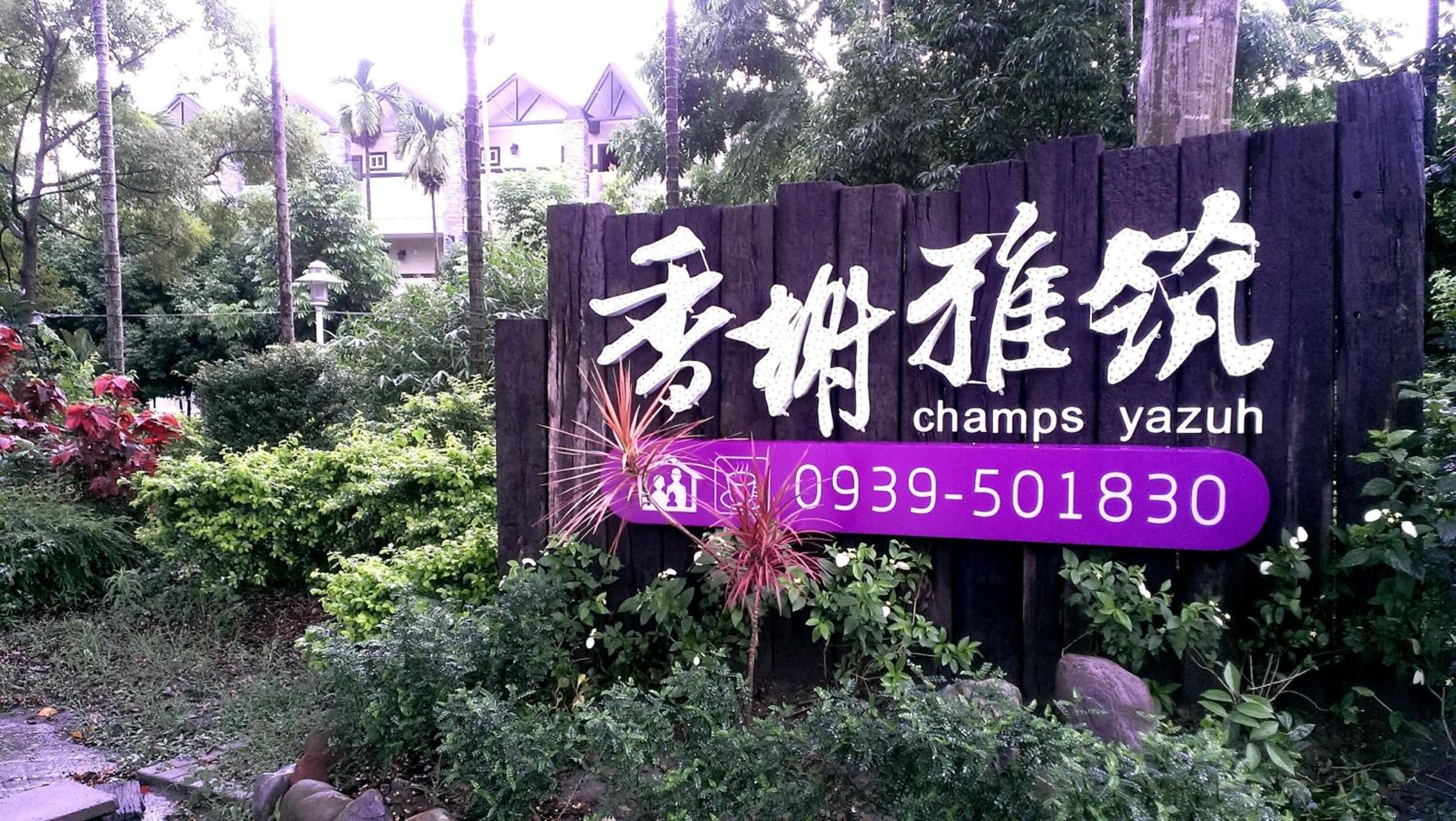 A wooden sign with Chinese characters and the name "champs yazuh" along with a phone number.