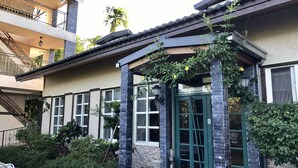 Een gebouw met een groene deur, een overdekte ingang en een trap die naar een balkon leidt.