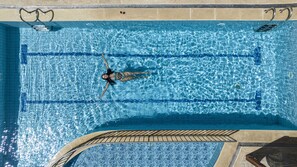 Una piscina al aire libre, sombrillas, sillones reclinables de piscina