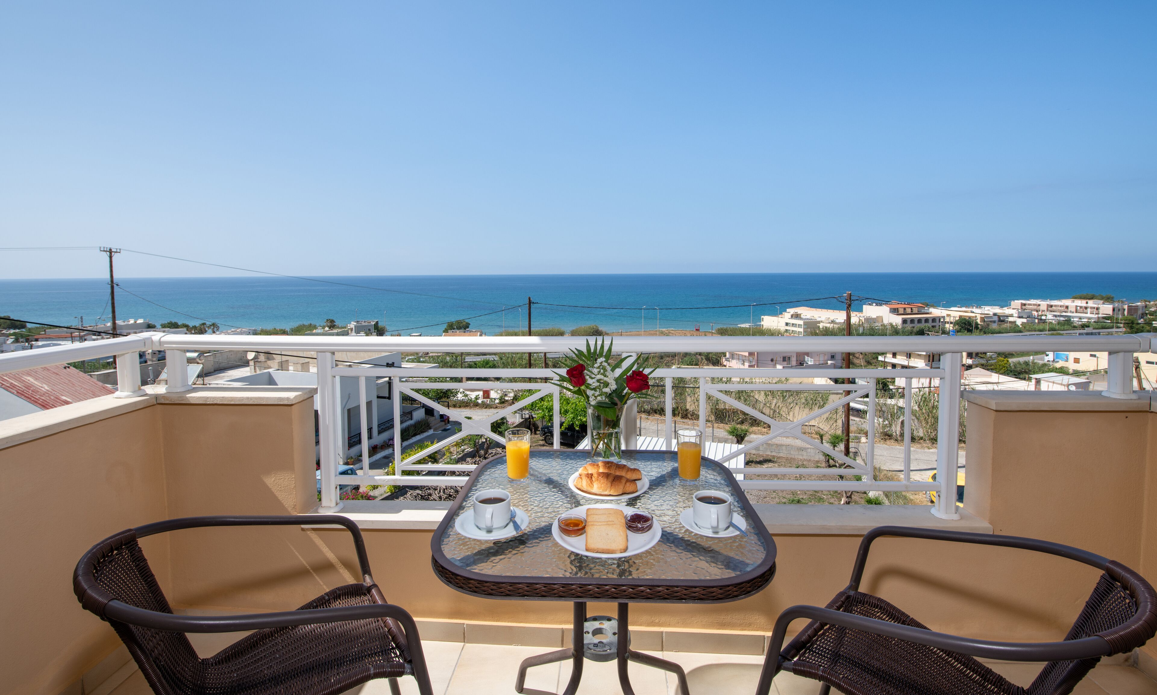 Ein Balkon mit Frühstückstisch, mit Blick auf die Küste.
