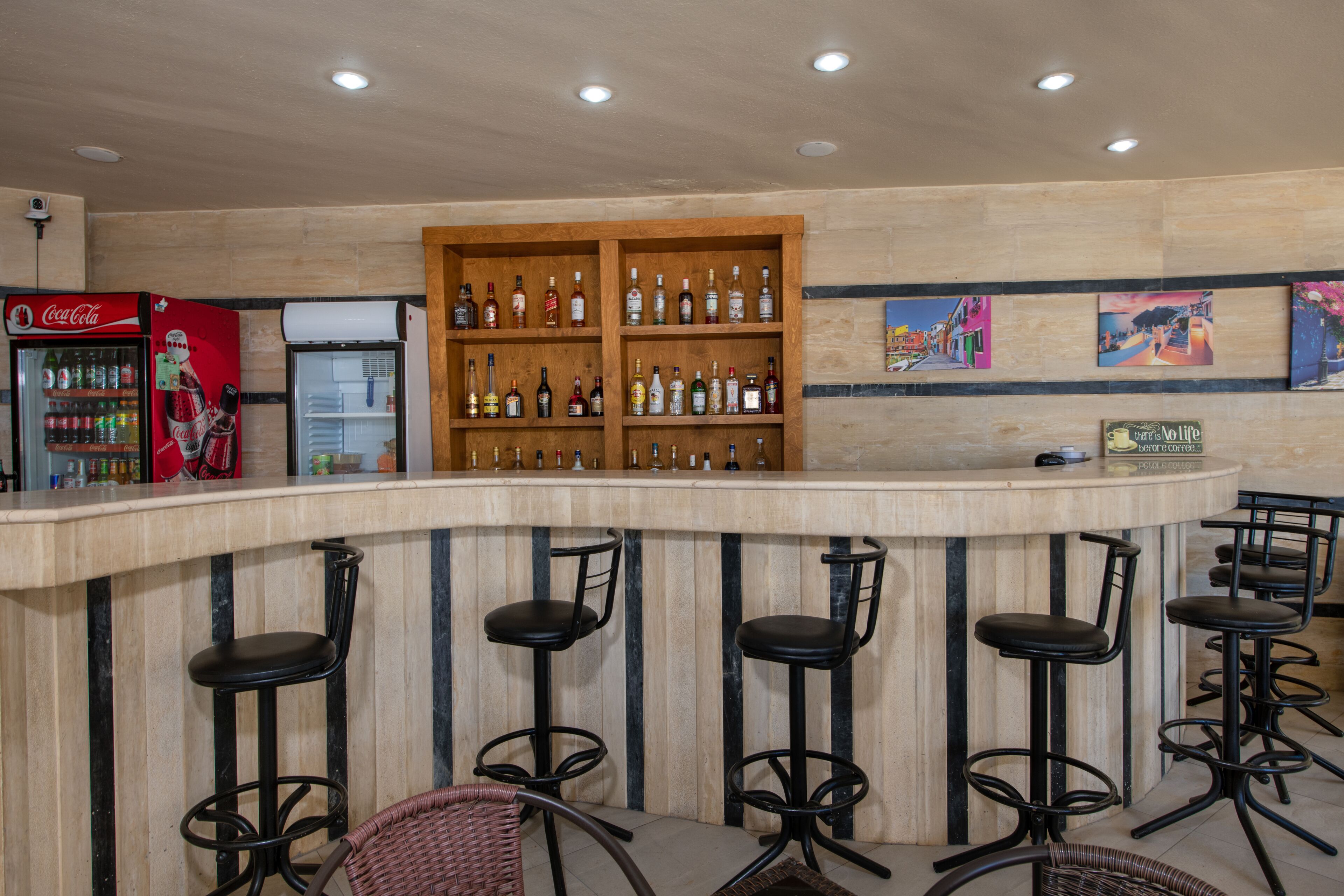 A bar area with a counter, shelves of bottles, and bar stools.