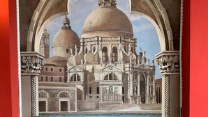 A mural of a grand building with domes and arches, a pool, and wicker chairs.