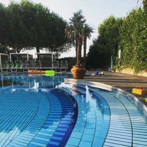 Una piscina al aire libre, sillones reclinables de piscina