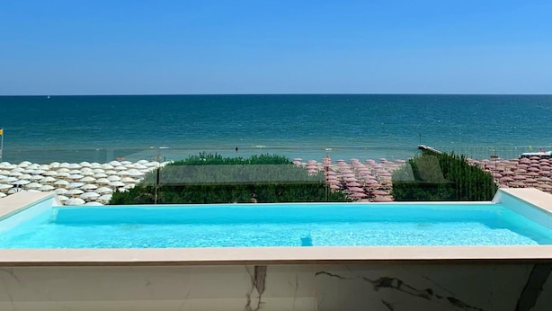 A pool with a view of the ocean and beach umbrellas.