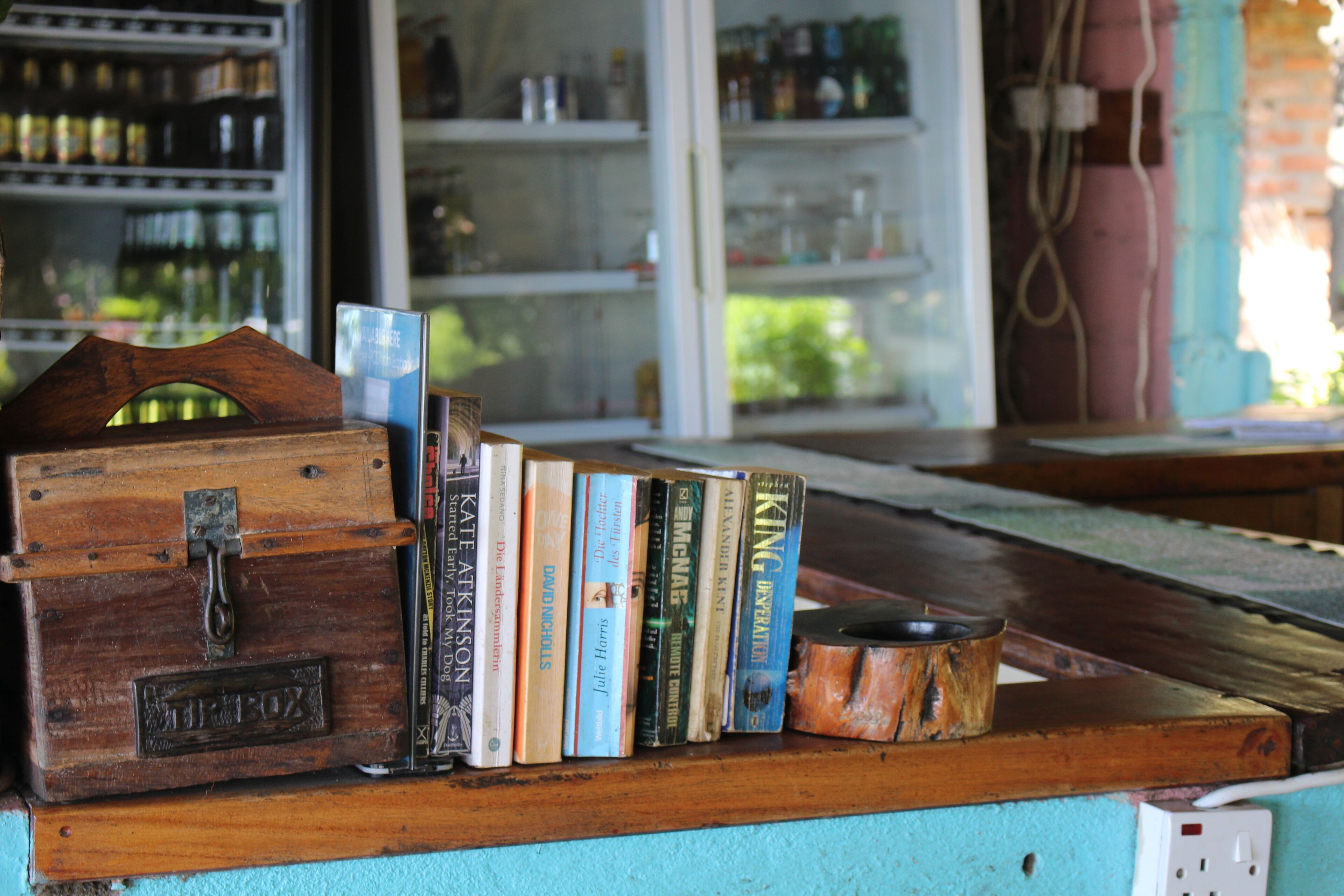 A wooden shelf with books and a vintage box labeled "TRIP BOX".