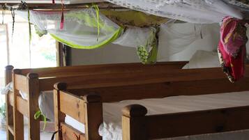 Cozy retreat with a wooden bunk bed, white linens, and a mosquito net for a comfortable stay.
