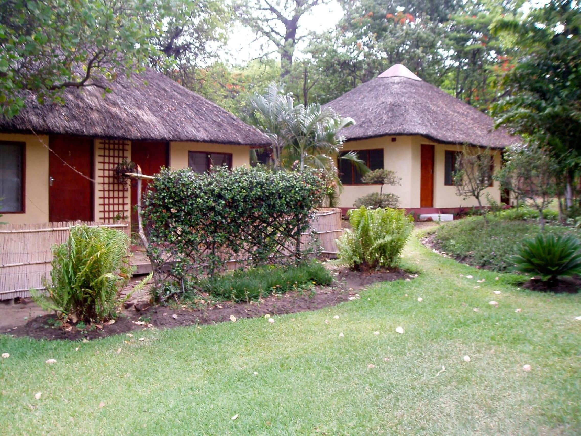 Two thatched-roof cottages with a garden in front.