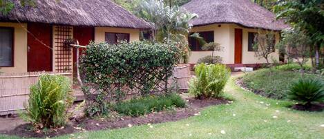 Two thatched-roof cottages with a garden in front.