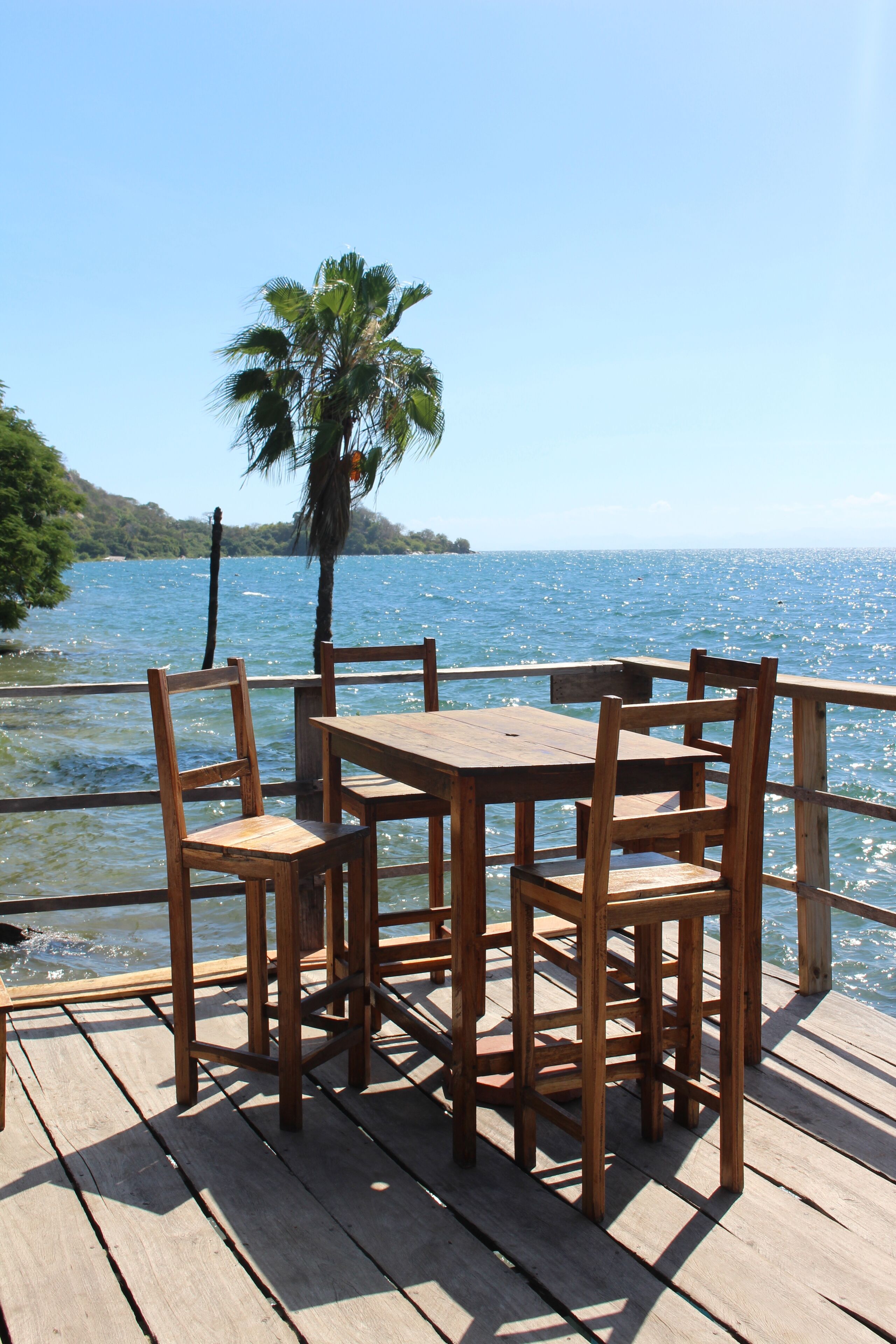 Een houten terras met een tafel en stoelen, uitkijkend op een wateroppervlak.