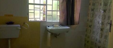 A bathroom with a window, sink, toilet, and shower curtain.
