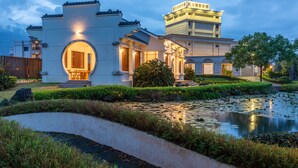 A traditional building with a large circular entrance, a pond with lily pads, and a well-maintained garden. - Hualien Toong Mao Resort (Ji'an)