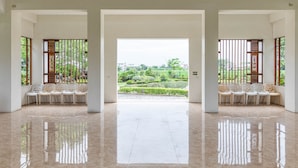 A spacious lobby with a polished floor, two seating areas with chairs, and a view of a landscaped garden through large windows. - Hualien Toong Mao Resort (Ji'an)