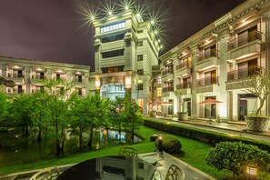Ein Hotel mit Innenhof, Teich und einer gut beleuchteten Fassade.