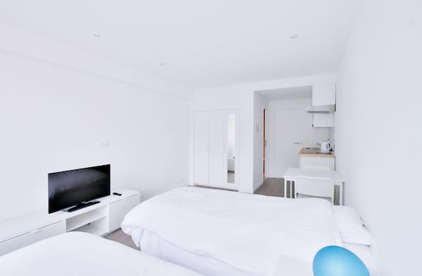 Ein modernes Hotelzimmer mit einem großen Bett, einem Fernseher, einem Schreibtisch und einem begehbaren Kleiderschrank.